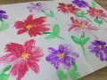 Des fleurs peintes en relief, rouges et violettes, avec des touches de jaune au centre. Une technique simple pour apprendre comment peindre des fleurs en relief.