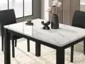 Table à manger moderne avec plateau marbre blanc et noir, chaises sombres et vase.