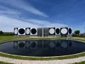 Le Centre d'art contemporain de Vassivière, avec ses façades ornées de cercles noirs et blancs, reflète les œuvres d'art de Victor Vasarely dans un étang paisible.