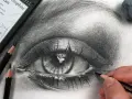 Un dessin d'œil réaliste au crayon graphite, avec des détails saisissants. L'artiste ajoute la touche finale à ce magnifique dessin oeil.