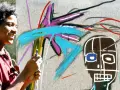 Un jeune homme souriant crée une œuvre d'art vibrante dans un style Basquiat, avec des couleurs vives et des formes audacieuses.