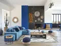 Un salon moderne avec un grand canapé bleu, une cheminée imposante et un tableau bleu marine sur le mur.