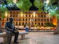 Statue de Picasso, rappelant ses origines, sur une place animée de Malaga la nuit, sous des arbres décorés de lumières.