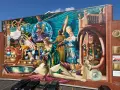 Fresque colorée représentant des personnages historiques et mythologiques, un artiste engagé qui dépeint la richesse culturelle.
