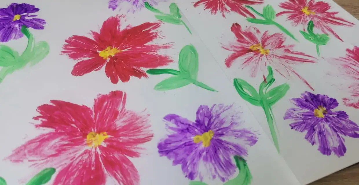 Des fleurs peintes en relief, rouges et violettes, avec des touches de jaune au centre. Une technique simple pour apprendre comment peindre des fleurs en relief.