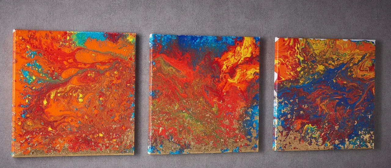 Trois toiles abstraites aux couleurs vives, un exemple de pouring art, avec des touches dorées.