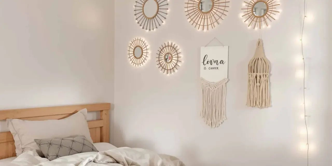 Un lit douillet avec des draps froissés, sur le mur, des miroirs soleil décoratifs et une guirlande lumineuse. Un tableau de nu noir et blanc est absent.