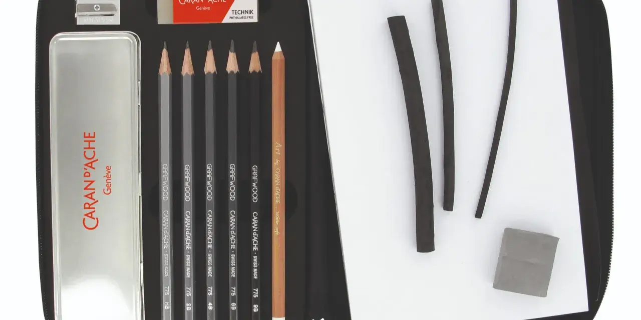 Étui ouvert révélant un matériel de dessin liste : crayons graphite, fusains, gomme et taille-crayon Caran d'Ache.