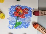 Apprenez comment utiliser les pastels à l'huile pour créer une fleur vibrante sur fond bleu. Des pastels jaune, rouge et orange sont visibles.