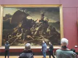 Un tableau crépuscule, "Le Radeau de la Méduse", montre des survivants désespérés sur un radeau. Des visiteurs contemplent cette œuvre dramatique.