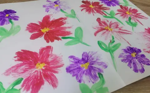 Des fleurs peintes en relief, rouges et violettes, avec des touches de jaune au centre. Une technique simple pour apprendre comment peindre des fleurs en relief.