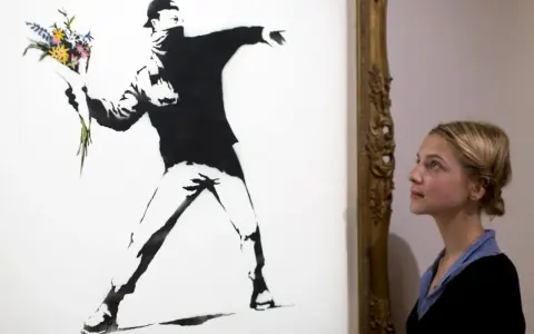 Une jeune femme admire "Flower Thrower", une œuvre emblématique de qui est Banksy, représentant un homme lançant un bouquet de fleurs.