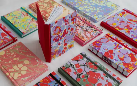Collection de carnets aux motifs marbrés colorés, évoquant le motif Annonay. Des couleurs vives et des formes organiques se mélangent sur les couvertures.