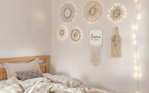 Un lit douillet avec des draps froissés, sur le mur, des miroirs soleil décoratifs et une guirlande lumineuse. Un tableau de nu noir et blanc est absent.