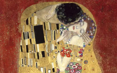 Le baiser de Klimt : un couple enlacé dans une étreinte dorée, sur fond rouge. L'homme enlace la femme, qui ferme les yeux, le visage baigné de lumière.