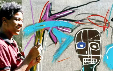 Un jeune homme souriant crée une œuvre d'art vibrante dans un style Basquiat, avec des couleurs vives et des formes audacieuses.