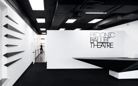 Un tableau danseuse moderne en mouvement dans un studio de ballet épuré, noir et blanc.