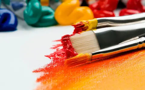 Pinceaux chargés de peinture rouge et jaune créent une œuvre vibrante. Idéal pour un débutant dessin peinture facile.