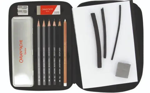 Étui ouvert révélant un matériel de dessin liste : crayons graphite, fusains, gomme et taille-crayon Caran d'Ache.