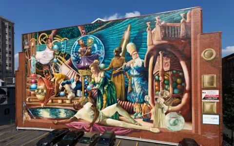 Fresque colorée représentant des personnages historiques et mythologiques, un artiste engagé qui dépeint la richesse culturelle.