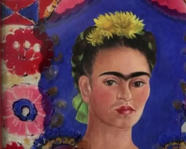 Portrait de Frida Kahlo, icône féministe, ornée de fleurs jaunes et d'un ruban vert, sur fond bleu vibrant et motifs floraux colorés.