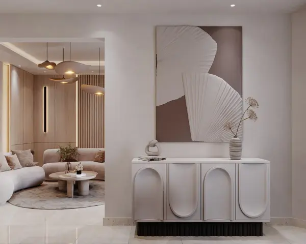 Un tableau marron beige abstrait orne un mur au-dessus d'un buffet moderne. Le salon adjacent est baigné de lumière douce.