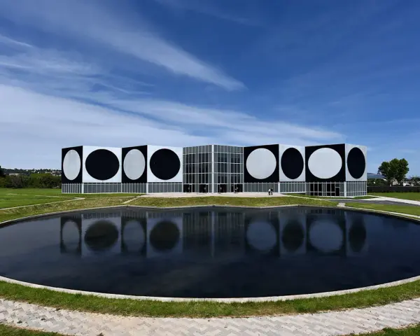 Le Centre d'art contemporain de Vassivière, avec ses façades ornées de cercles noirs et blancs, reflète les œuvres d'art de Victor Vasarely dans un étang paisible.