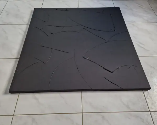 Une toile texturée, d'un noir absolu, aux courbes abstraites et profondes, posée sur un sol carrelé.
