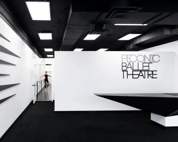 Un tableau danseuse moderne en mouvement dans un studio de ballet épuré, noir et blanc.