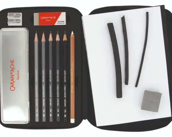 Étui ouvert révélant un matériel de dessin liste : crayons graphite, fusains, gomme et taille-crayon Caran d'Ache.