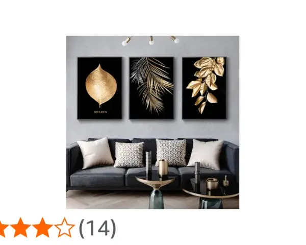Un salon moderne avec un canapé gris, des coussins décoratifs et un triptyque **tableau noir et or** de feuilles dorées sur fond noir.