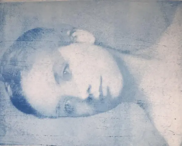 Portrait d'une personne en gros plan, réalisé par transfert photo sur gelli plate. L'image est en tons bleus, avec des textures et des lignes visibles.