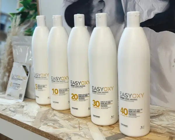Cinq bouteilles d'oxydant EasyOxy, aux teintes gris marron sur l'étiquette, alignées sur une étagère en bois.