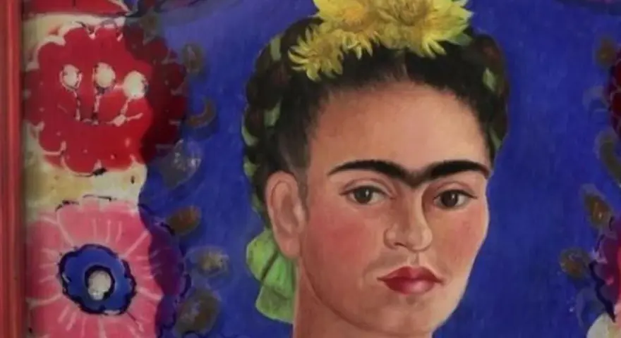 Portrait de Frida Kahlo, icône féministe, ornée de fleurs jaunes et d'un ruban vert, sur fond bleu vibrant et motifs floraux colorés.