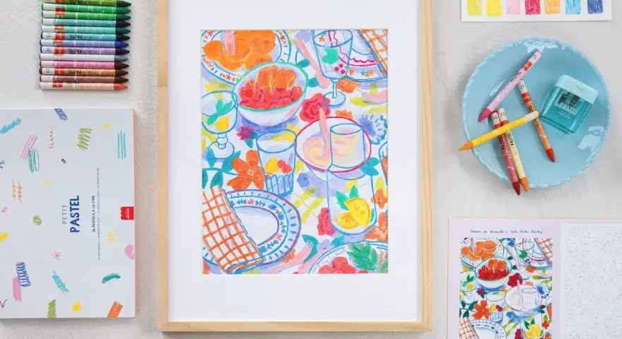 Un dessin pastel facile à faire d'une table de pique-nique colorée, entouré de pastels, d'une boîte et d'un livre de coloriage.