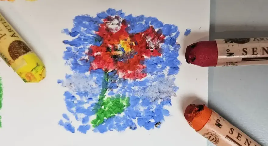 Apprenez comment utiliser les pastels à l'huile pour créer une fleur vibrante sur fond bleu. Des pastels jaune, rouge et orange sont visibles.