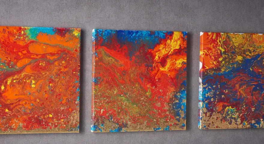 Trois toiles abstraites aux couleurs vives, un exemple de pouring art, avec des touches dorées.