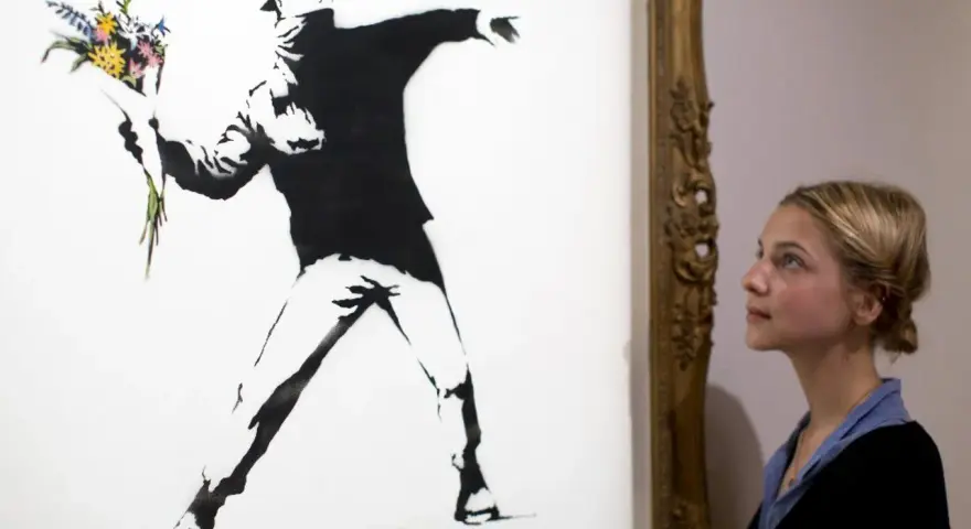 Une jeune femme admire "Flower Thrower", une œuvre emblématique de qui est Banksy, représentant un homme lançant un bouquet de fleurs.