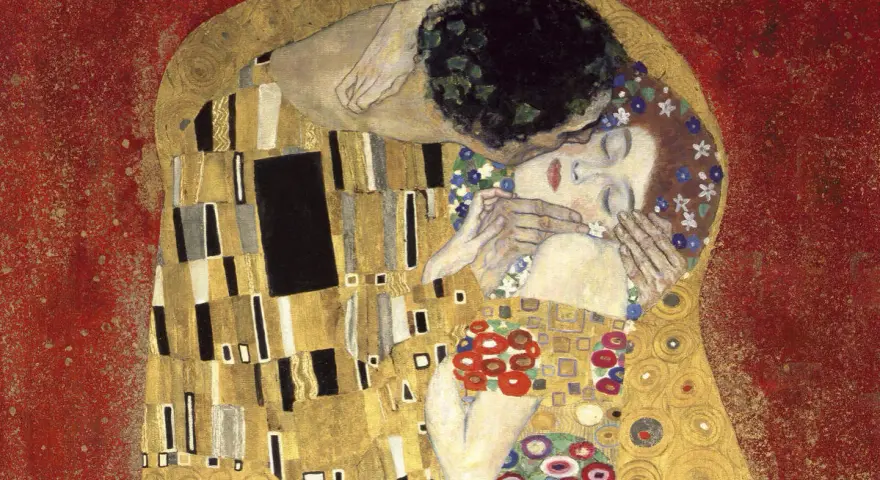 Le baiser de Klimt : un couple enlacé dans une étreinte dorée, sur fond rouge. L'homme enlace la femme, qui ferme les yeux, le visage baigné de lumière.