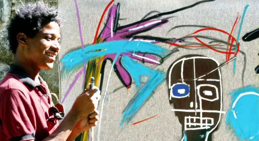 Un jeune homme souriant crée une œuvre d'art vibrante dans un style Basquiat, avec des couleurs vives et des formes audacieuses.