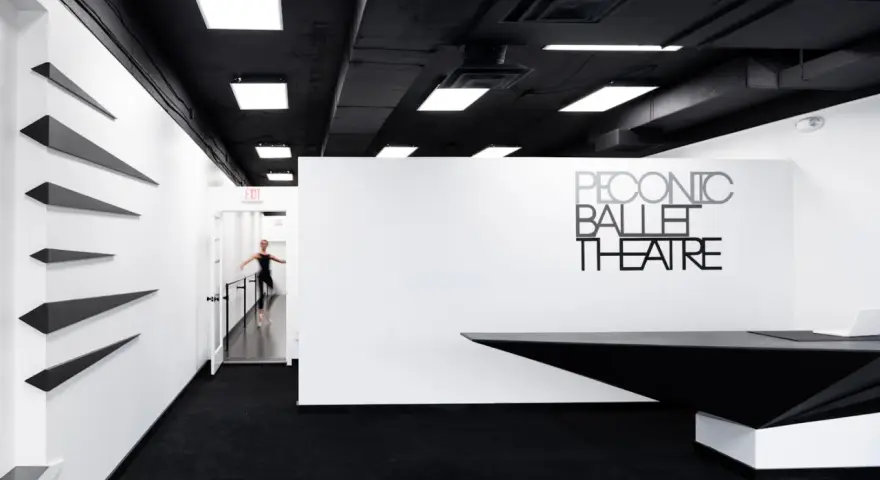 Un tableau danseuse moderne en mouvement dans un studio de ballet épuré, noir et blanc.