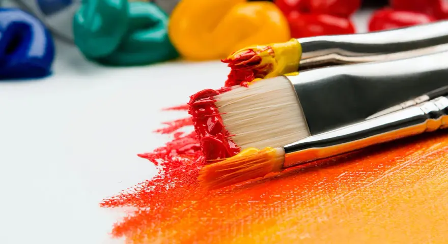 Pinceaux chargés de peinture rouge et jaune créent une œuvre vibrante. Idéal pour un débutant dessin peinture facile.