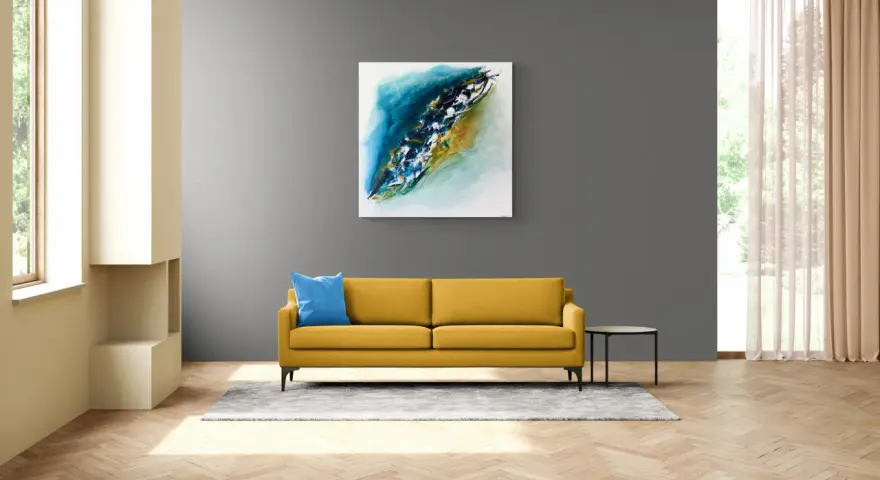 Un tableau grand format abstrait aux tons bleus et dorés domine un salon moderne. Un canapé jaune vif et un coussin bleu apportent une touche de couleur.