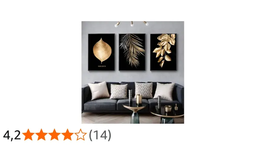 Un salon moderne avec un canapé gris, des coussins décoratifs et un triptyque **tableau noir et or** de feuilles dorées sur fond noir.