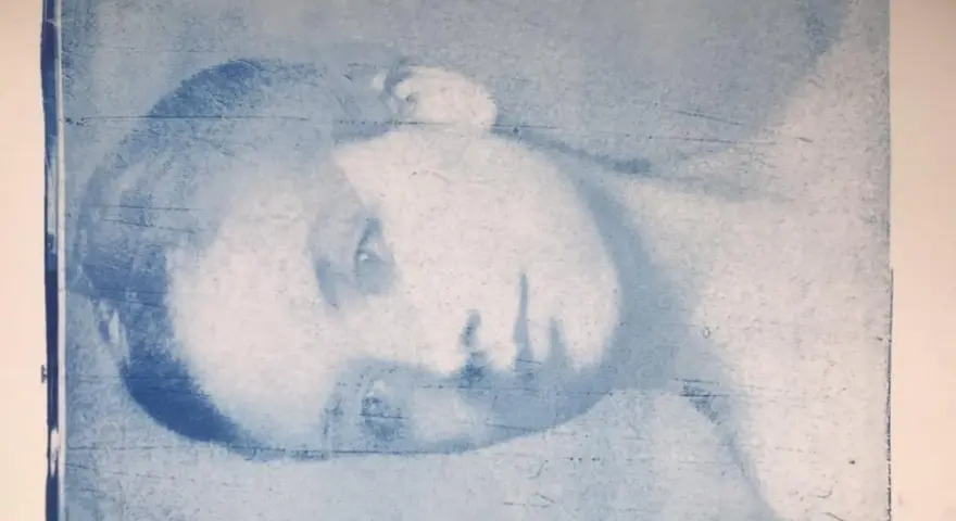 Portrait d'une personne en gros plan, réalisé par transfert photo sur gelli plate. L'image est en tons bleus, avec des textures et des lignes visibles.