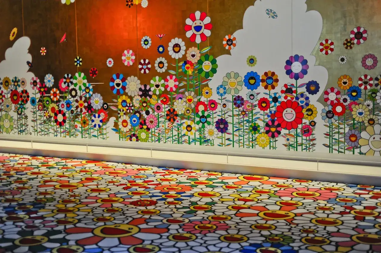Un mur et un sol recouverts de fleurs souriantes color&eacute;es, signature de l'artiste Murakami.