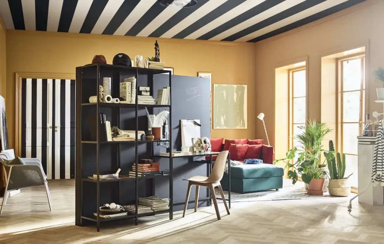 Un salon moderne avec un tableau cactus, des &eacute;tag&egrave;res noires, un canap&eacute; rouge et des plantes vertes.