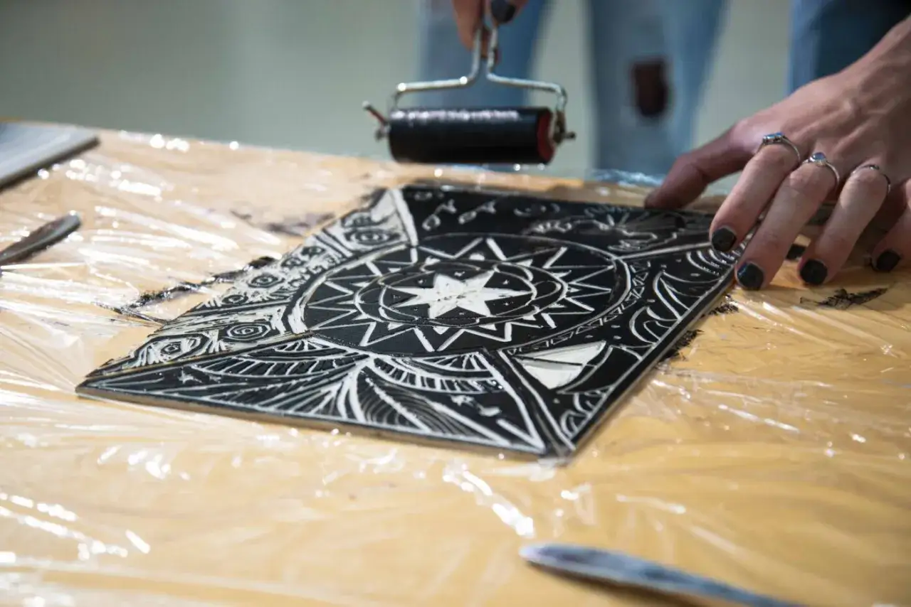 Application d'encre sur une plaque grav&eacute;e, montrant les diff&eacute;rents types de gravure. Une main pr&eacute;pare l'estampe.