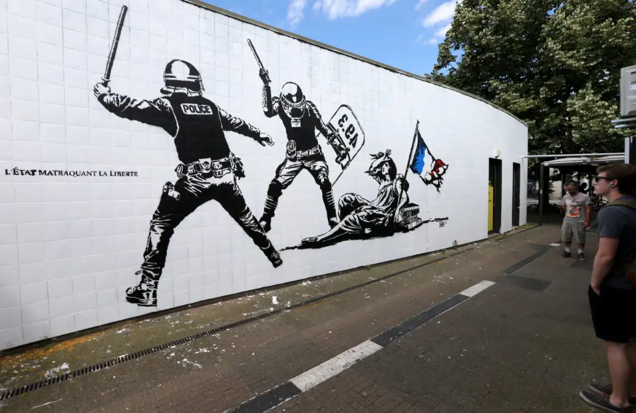 &OElig;uvre d'un artiste engag&eacute; : deux policiers anti-&eacute;meute matraquent une figure all&eacute;gorique de la Libert&eacute;, drapeau fran&ccedil;ais en main.