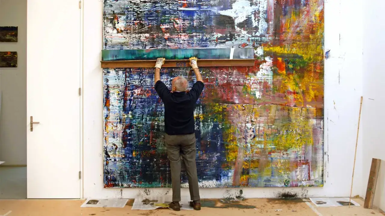 Un artiste, peut-&ecirc;tre Gerhard Richter, utilise une raclette pour cr&eacute;er des &oelig;uvres d'art abstraites vibrantes.